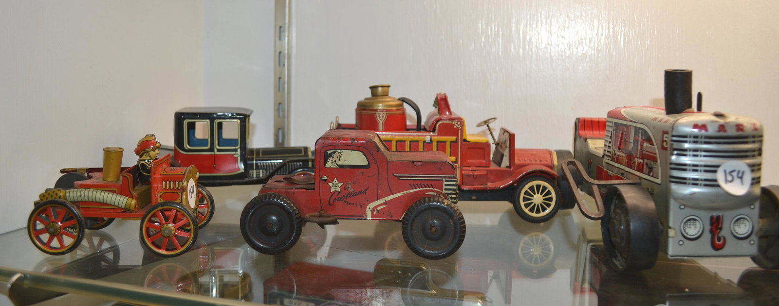 Five Vintage Tin Litho Vehicles: A Marx working wind up tractor missing rider, a Land of Lincoln friction fire truck, two Japanese friction vehicles and a Cortland wind up truck functioning but missing cab.