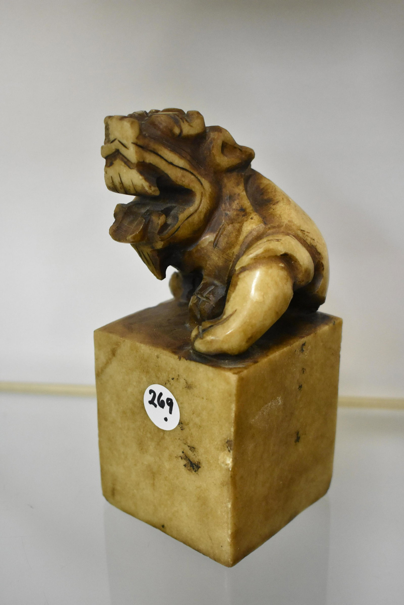 Carved Stone Foo Dog Ink Stamp: Measures approx. 7"h. It depicts a Foo dog and has a square base. Bottom is an ink stamp. Item is carved from a single piece of stone and has a few small dings around cube.