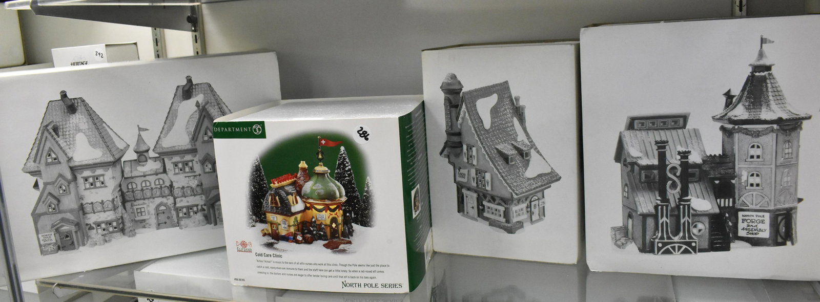 Dept 56 North Pole Series NIB: North Pole Dolls and Santa's Bear Works, Elfin Forge and Assembly Shop, Elfin Snow Cone Works and The Cold Care Clinic. Four items.