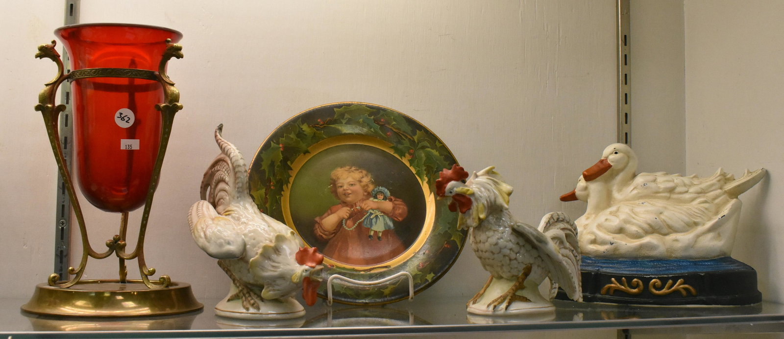 Decorative Items: including contemporary cast iron painted duck doorstop, two German ceramic fighting cocks, a tin plate with image of child holding doll, a red glass and brass epergne with birds on frame.