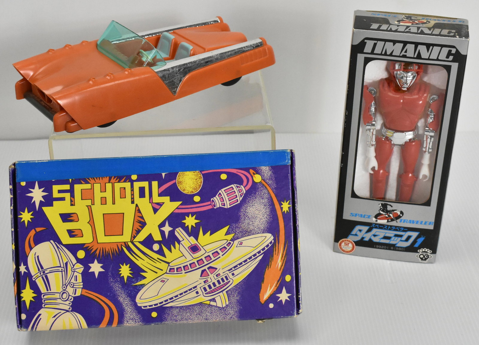 Red Timanic Robot, Mattel Space Car & Pencil Box: Includes Takara Timanic Space Traveler in red #199201 (980) in original windowed box, broken helmet plastic and an orange Mattel Space Car, circa 1950's, plus school space pencil box circa 1950's,