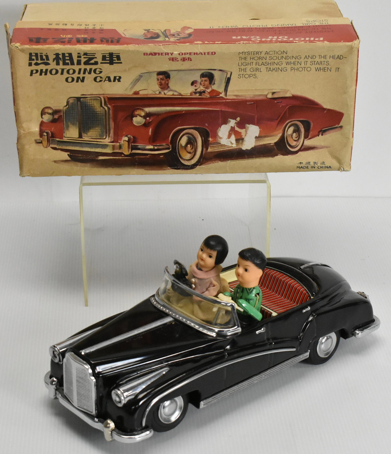 Photo'ing on Car Battery Operated Toy: Tin litho mystery action, horn sounds, headlight flashing, girl takes photo when stops, made in China, in original box (as found), toy in good condition (guys arms are loose), ME630
