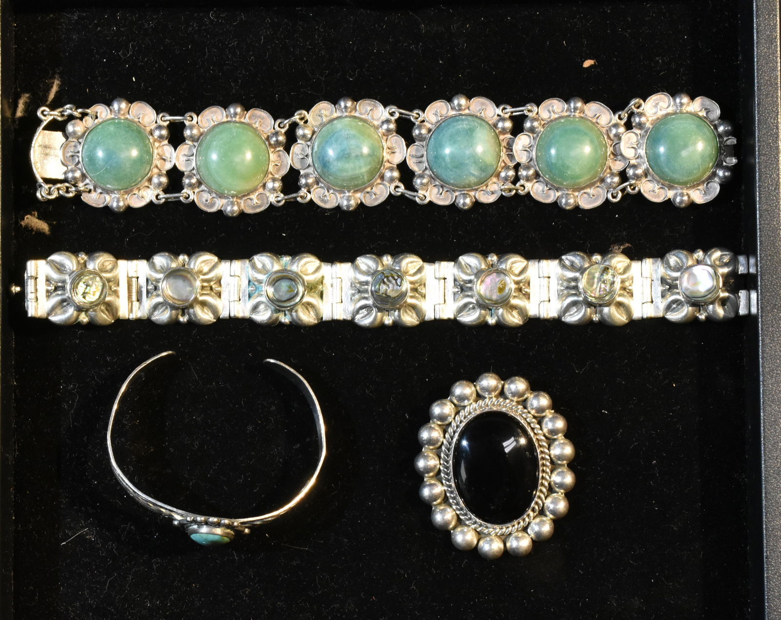 Mexican Sterling Jewelry Grouping: Including a bracelet with abalone stones, a bracelet with aqua stones, a small bracelet with turquoise stones and brooch with onyx stones.