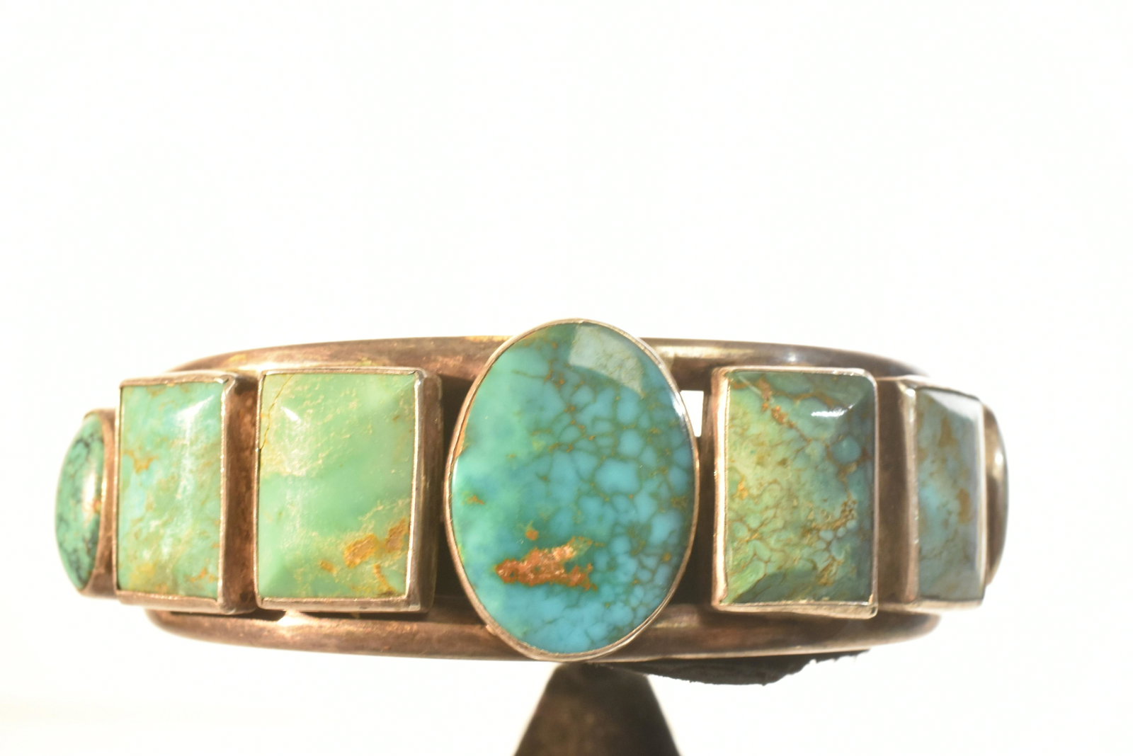 Outstanding Native American Cuff: Outstanding blue and green stones consisting of a large central stone surrounded by four rectangular stones and two oval stones. There is a blossom at the end of each cuff and a sunshine face with mak