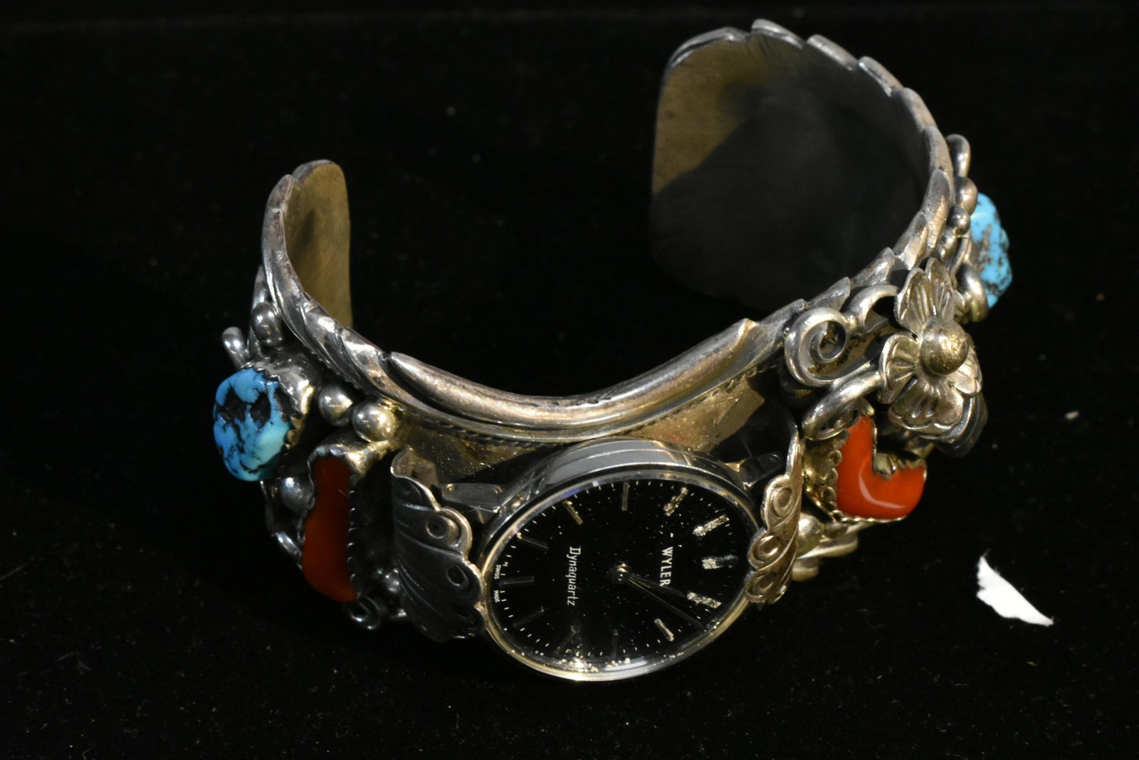 Apachito Heavy Ornate Watch Cuff: Cuff is set with turquoise, coral stones and a bear claw. It has an ornate floral and vine design and contains a Wyler Dynaquartz Swiss made watch.