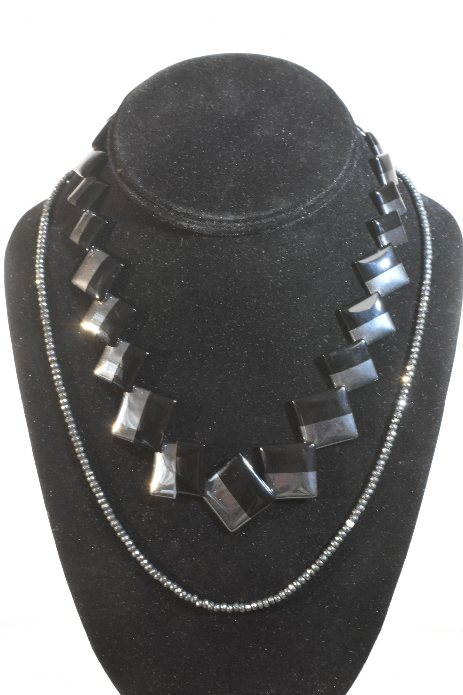 Two Quality Hematite Necklaces: One has onyx and hematite geometric stones with a 14K gold closure and the other is beaded hematite with a bronze closure.