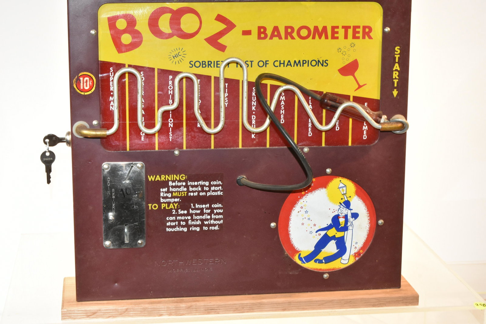 North Western Electric Booz Barometer 10 Cent: Measures approx. 17 1/2"h x 18"w x 4"d. It has a metal body with good graphics, working lock and key, base has been replaced and is battery operated. Item comes with original box - box is damaged.