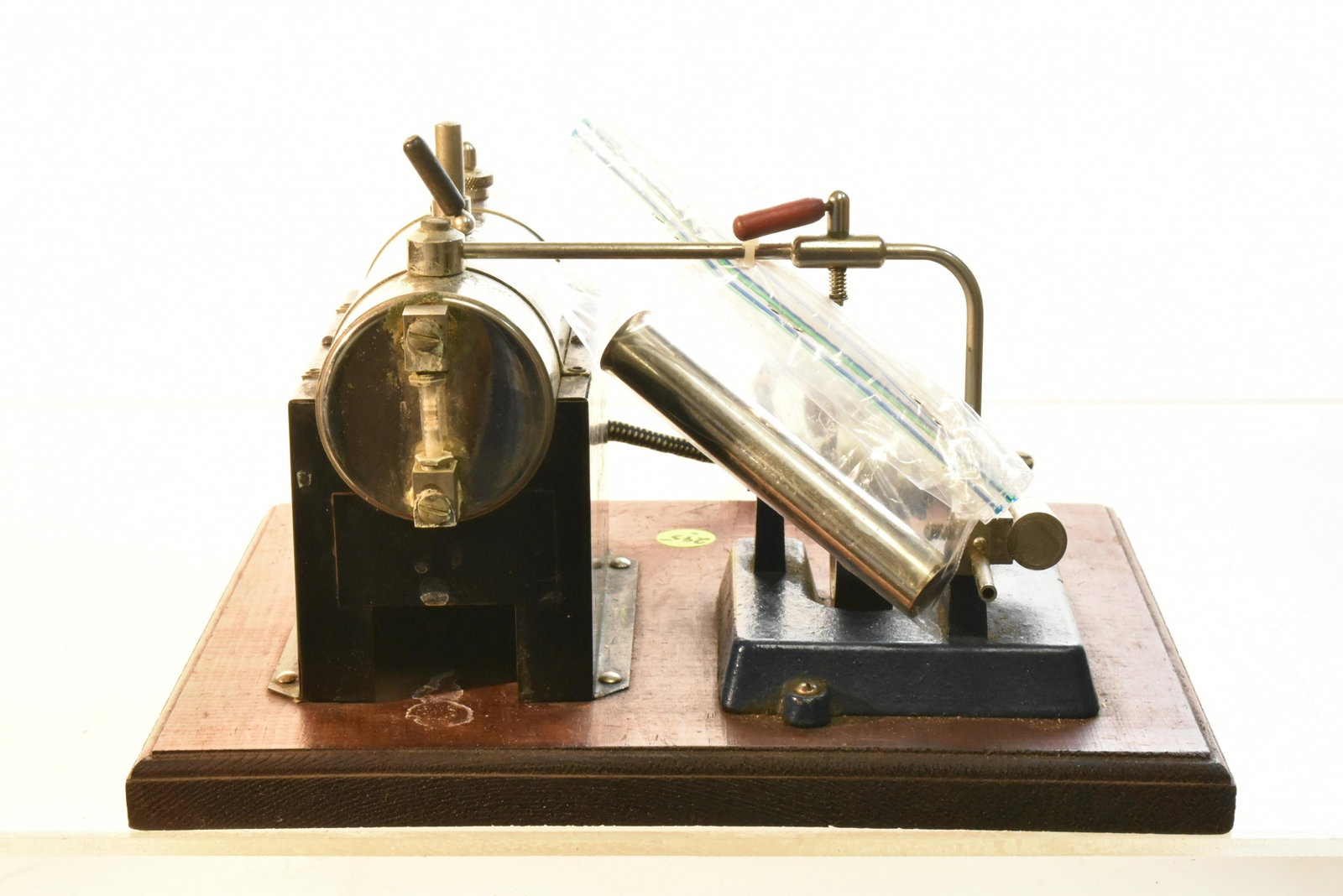 Jensen Electric Steam Toy: Measures approx. 6"h. Item is a metal steam toy with a drive wheel complete with smoke stack and original base with tag reading "Jensen Mfg Co Jeannette, Pa splits AC or DC".