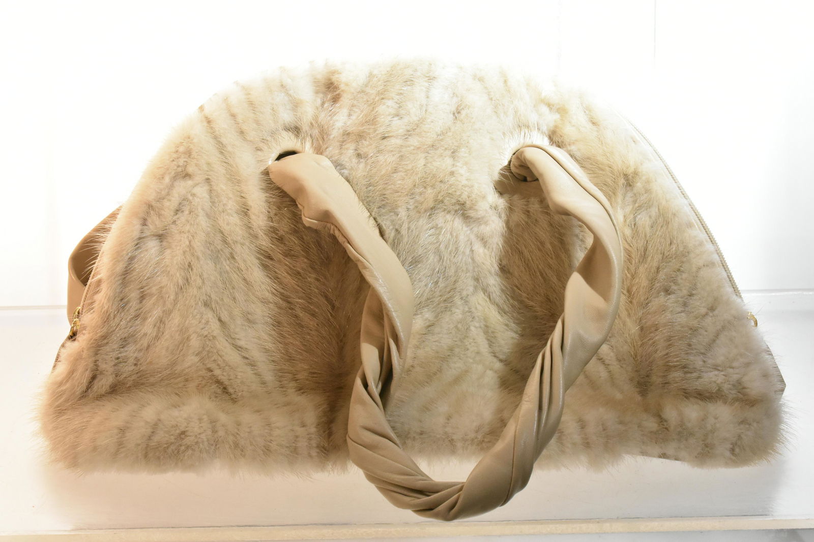 Paolo Masi Mink and Leather Handbag: Mink bodied and leather handled handbag with a leather bottom, silk interior, brass and woven logos on interior and a zippered closure.