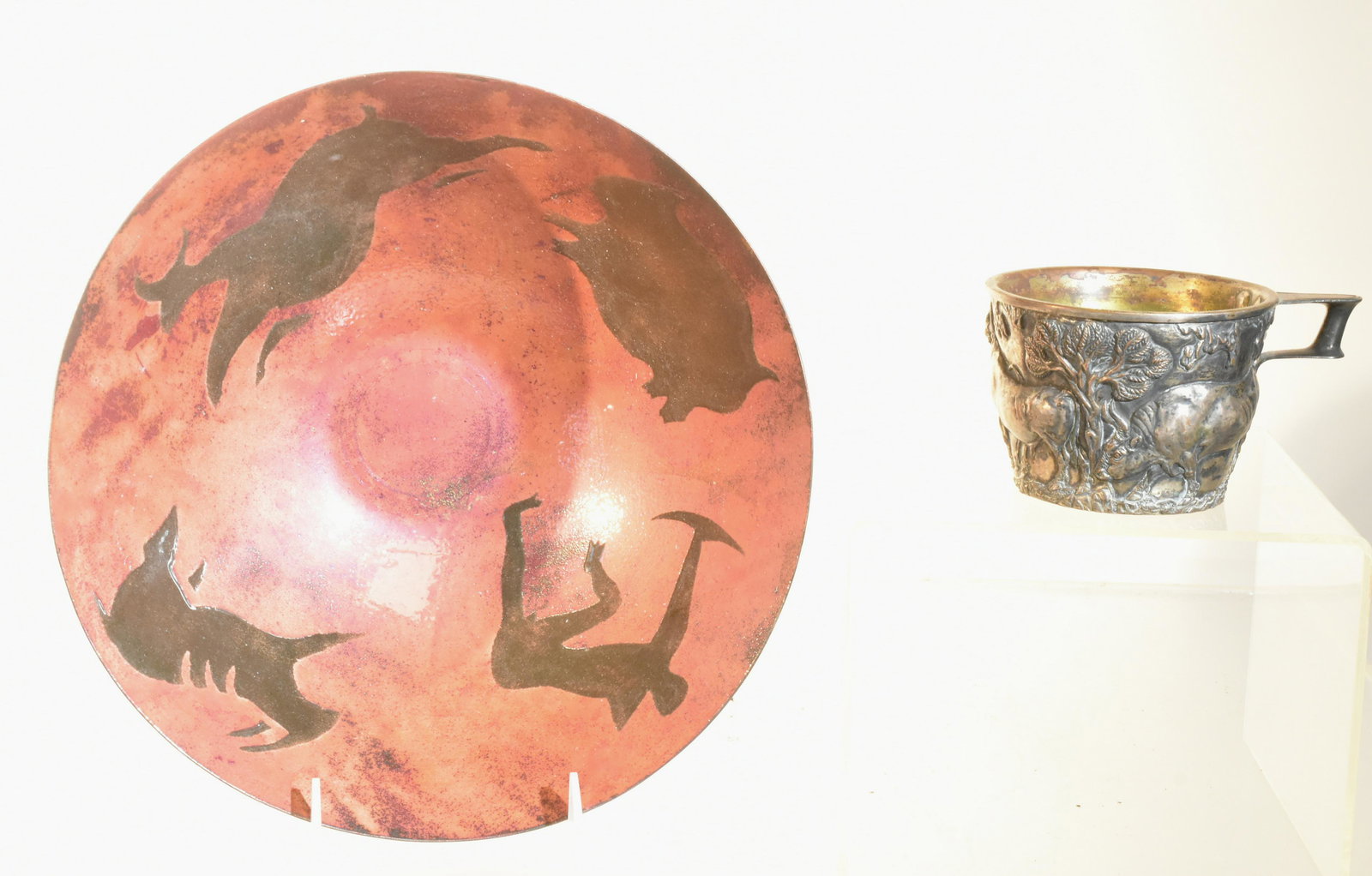 Enameled Copper Bowl Signed Culp: Item measures approximately 4"H x 11" diameter. The interior depicts a hunter with bow and arrow, and three animals. It has a mauve glaze and it is signed Culp on the bottom. Lot also includes a mug w