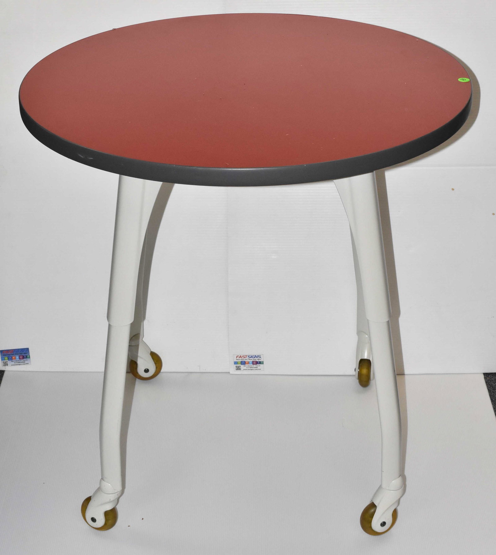 Allsteel Post Modern Style Side Table: Item measures approximately 30"H x 30" in diameter. Item has a red top, metal splay legs and bearing wheels. Item was delicately used.