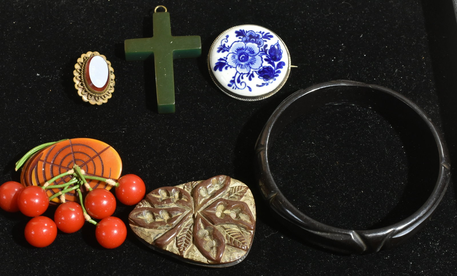 Bakelite and Sterling Jewelry: Lot includes bakelite jewelry, a cherry pin, a fur clip, a car black bangle, and a cross. Lot also includes a delft pin with sterling frame, and a brass pin with bakelite center.