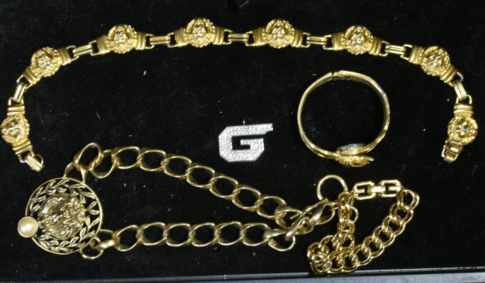 Givenchy Lion Head Jewelry: Lot includes a 1979 Givenchy whistle pendant, with clear rhinestones, a gold tone bracelet with signature logo on clasp, (2) lion head necklaces, and a cat watch bracelet, with green stone eyes. Not a