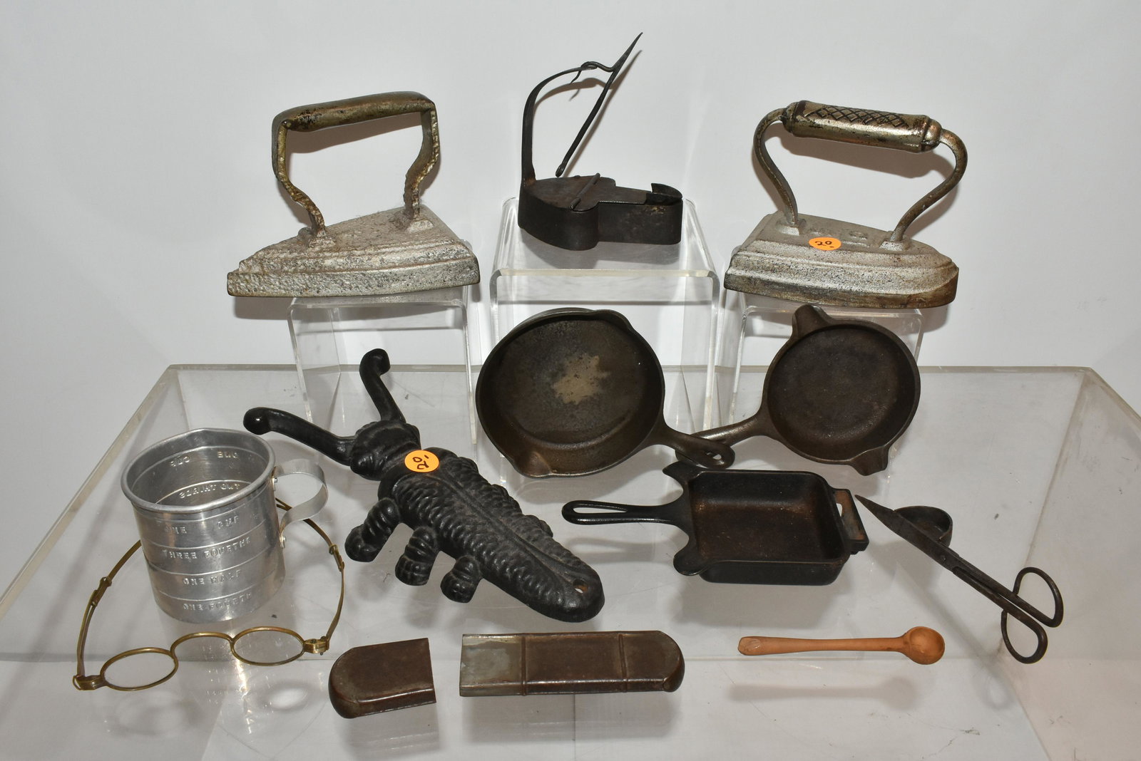 Betty Lamp and Other Country Items: Lot includes a 19th C Betty lamp, a pair of brass framed spectacles, a Griswold advertising ashtray, (2) miniature Wagner pans, and other related items.
