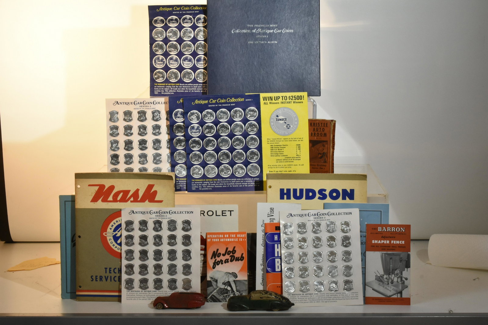 Automotive Advertising and Collectibles: Lot includes a 1955 Nash Manual, 1956 Hudson Manual, 1953 Chevy Catalog, Sunoco Auto Coins, auto broom in original pack, 2 Auburn rubber cars, and more.