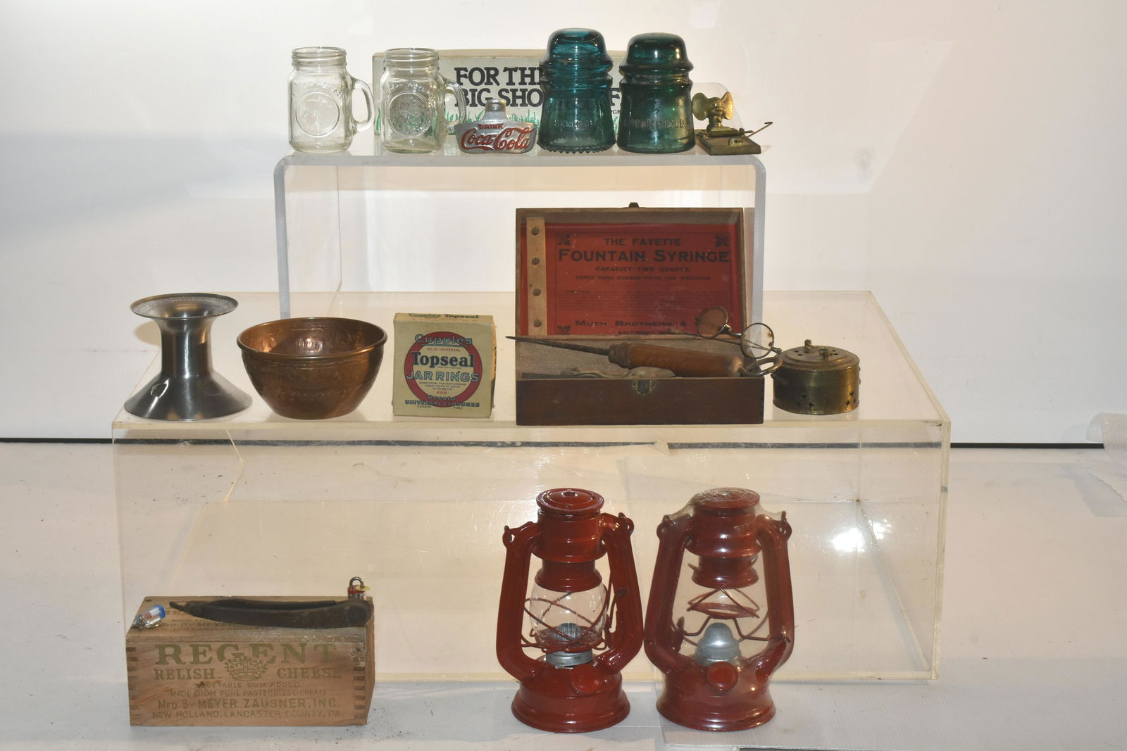 (2) Trays of Mixed Country Collectibles: Lot includes a pair of vintage eyeglasses, a straight razor, (2) contemporary oil lanterns, insulators, a Coca Cola bottle opener, and more.