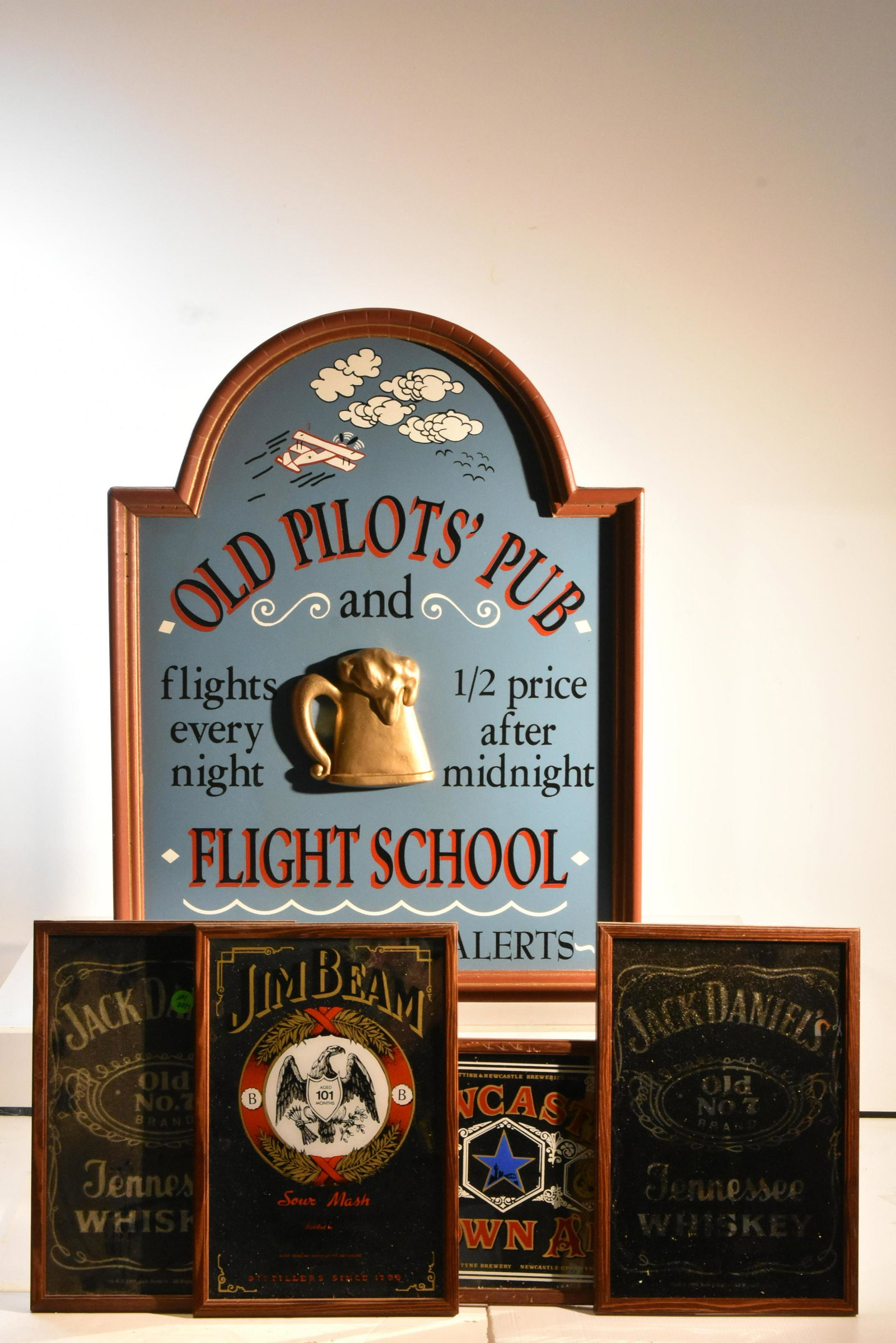 Pub and Alcohol Advertising Grouping: Lot includes a wooden frame Old Pilot's Pub sign measuring approximately 24"H x 18"W, (2) Jack Daniels advertising mirrors, a Jim Beam mirror, and a New Castle Brown Ale mirror.