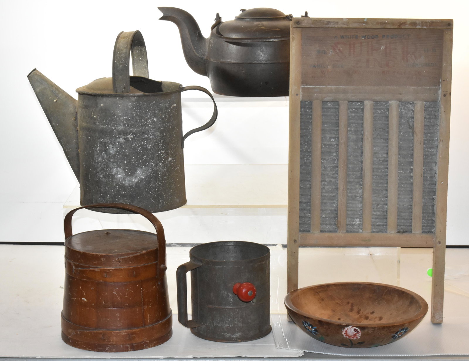 Mixed Country Grouping: Lot includes a firkin sewing basket, a cast iron tea kettle (early 20th C), a Marquette treen bowl, a sifter, a washboard, and a watering can missing nozzle.