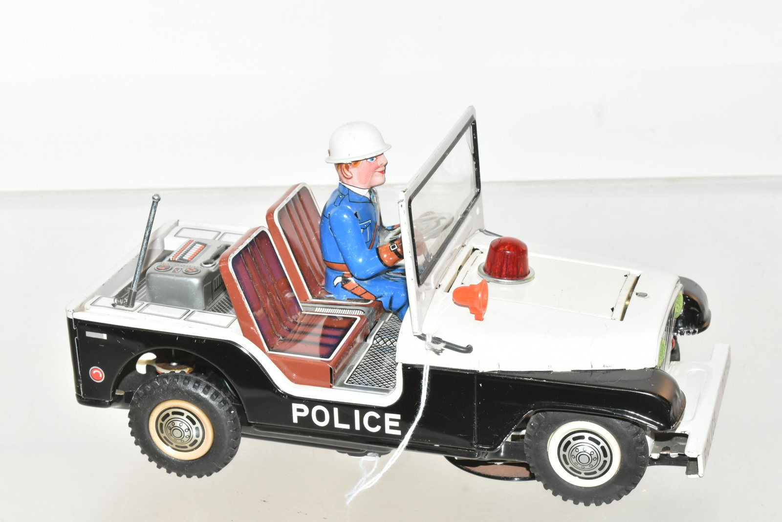 Tin Litho Battery Operated Police Jeep: Item measures approximately 10.5"L. It has good graphics, rubber wheels, and light on hood reverses to expose machine gun. Toy is in clean condition.