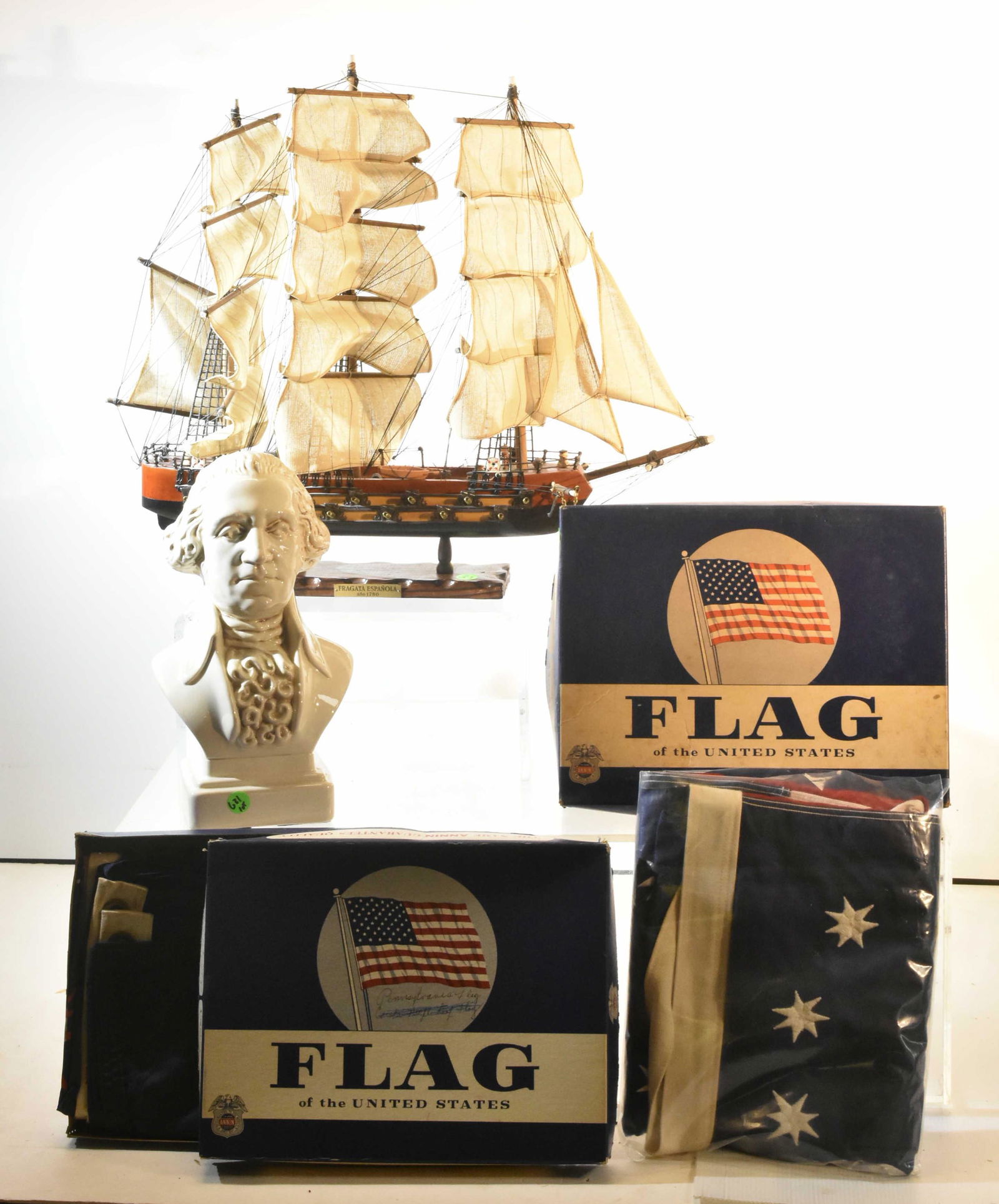 Cotton Flags, a Model, and More: Lot includes 4x6 cotton Pennsylvania flags, 5x8 cotton US flag, a bust of George Washington, and a model frigate with wooden body and cloth sails.