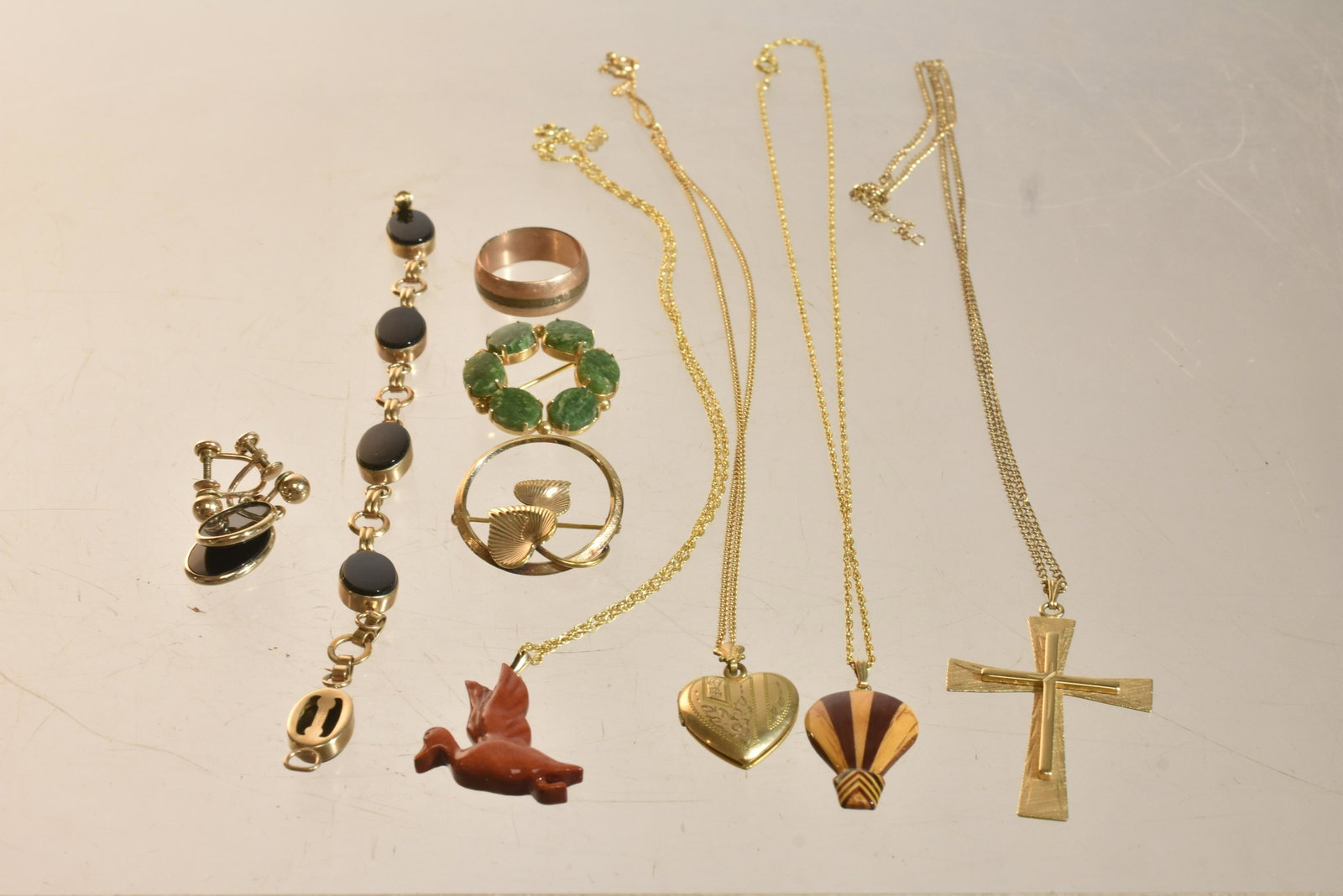 Gold Filled Jewelry Grouping: Lot includes bracelet with black stones, necklace with cross, gold filled chains with wooden pendants, a gold filled locket, and other gold filled items.