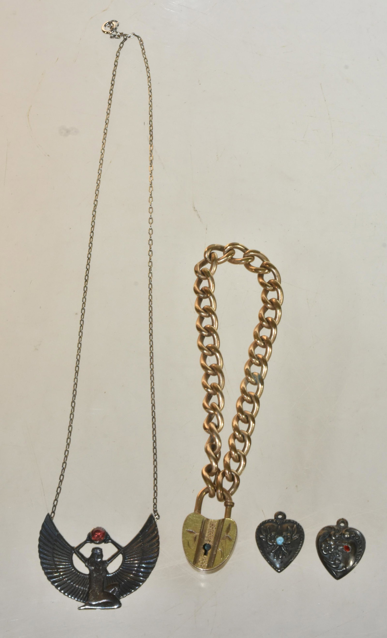Victorian and Silver Jewelry: Lot includes an Egyptian revival style sterling necklace with garnet, a Victorian curve link heart locket bracelet, and (2) sterling silver stone set heart charms.