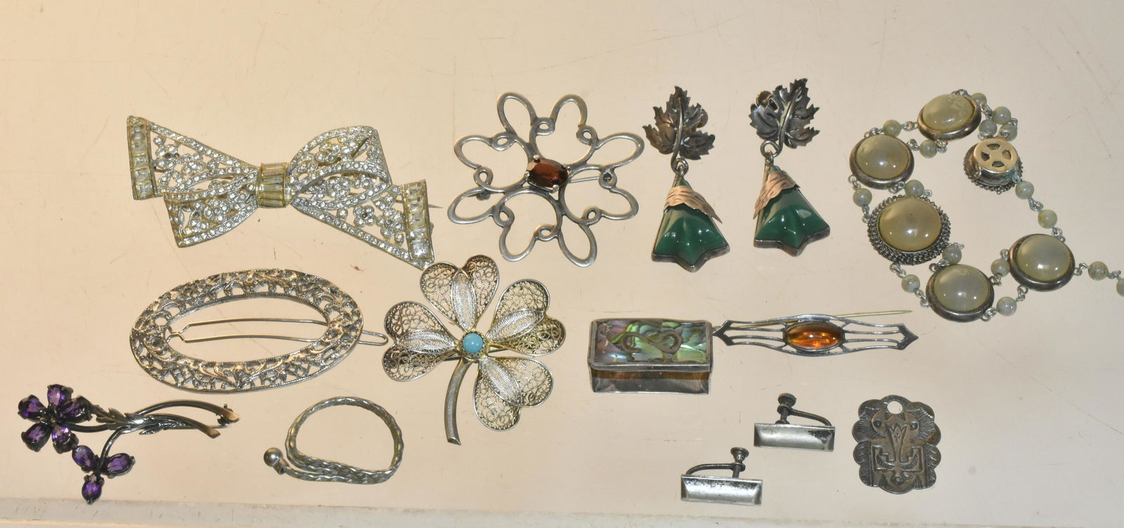 Sterling and Other Jewelry: Lot includes an .800 silver four leaf clover pin, sterling pin with red stone, a sterling belt clip with abalone inlay, Mexican sterling earrings with green stones, small sterling totem pendant, sterl