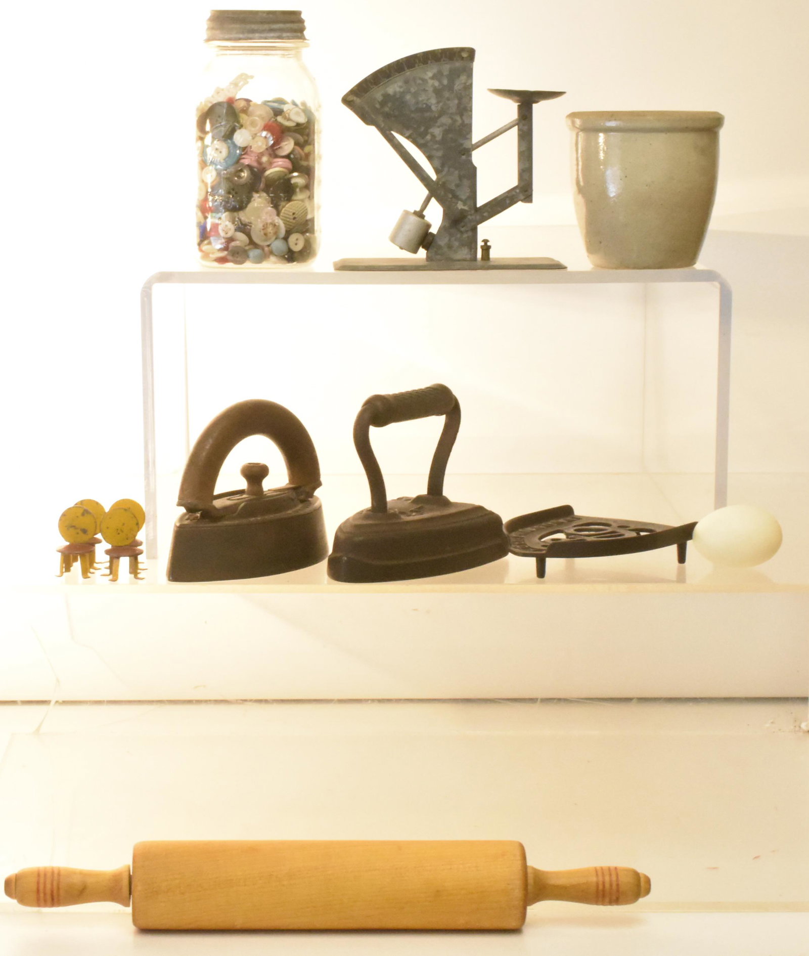 Sad Irons, Buttons, Country Kitchen Items: Lot includes a galvanized egg scale, a jar of buttons, (2) sad irons, a trivet, a crock, a rolling pin, and a plastic egg.