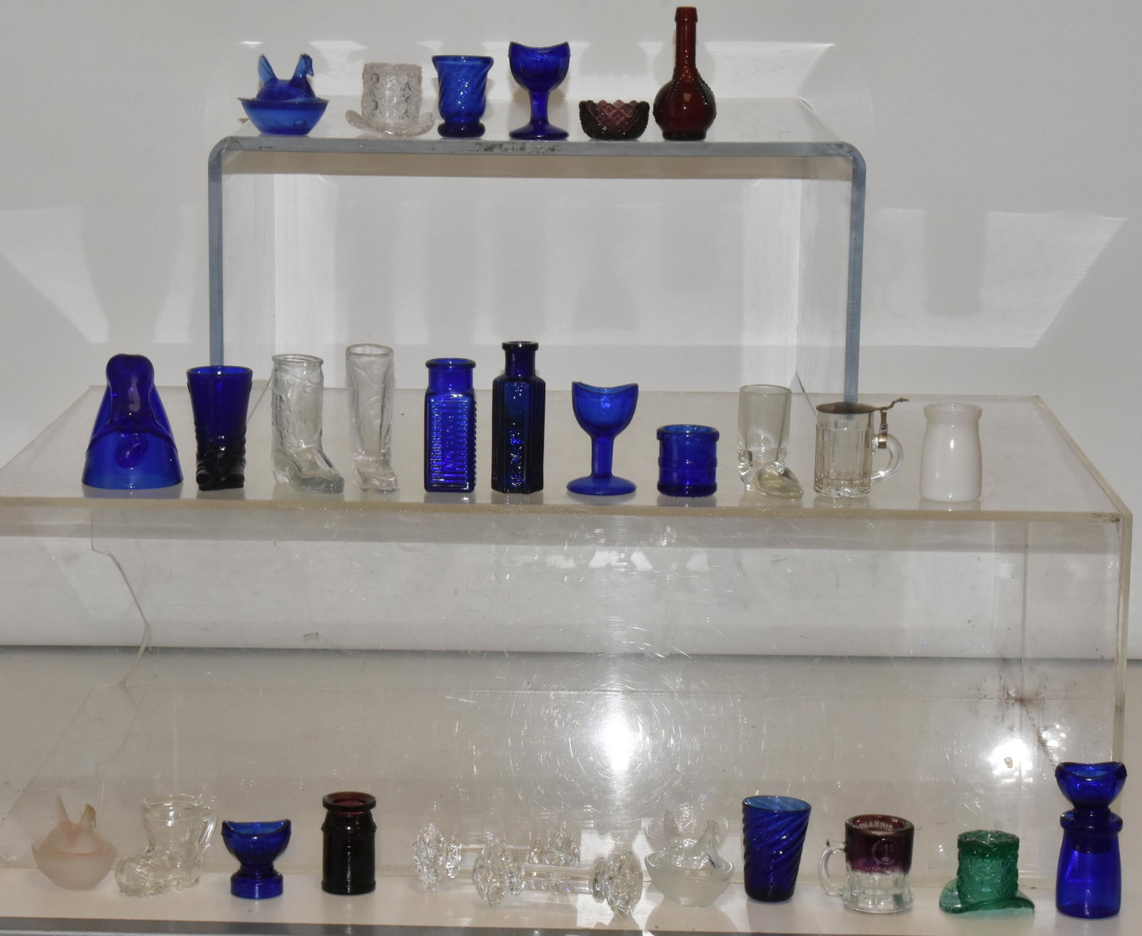 Cobalt and Other Miniature Glassware: Lot includes cobalt nude "Bottoms Up" glass, eyewash glasses, miniature boots, chickens on nest and more. Most items are from the 1980's.