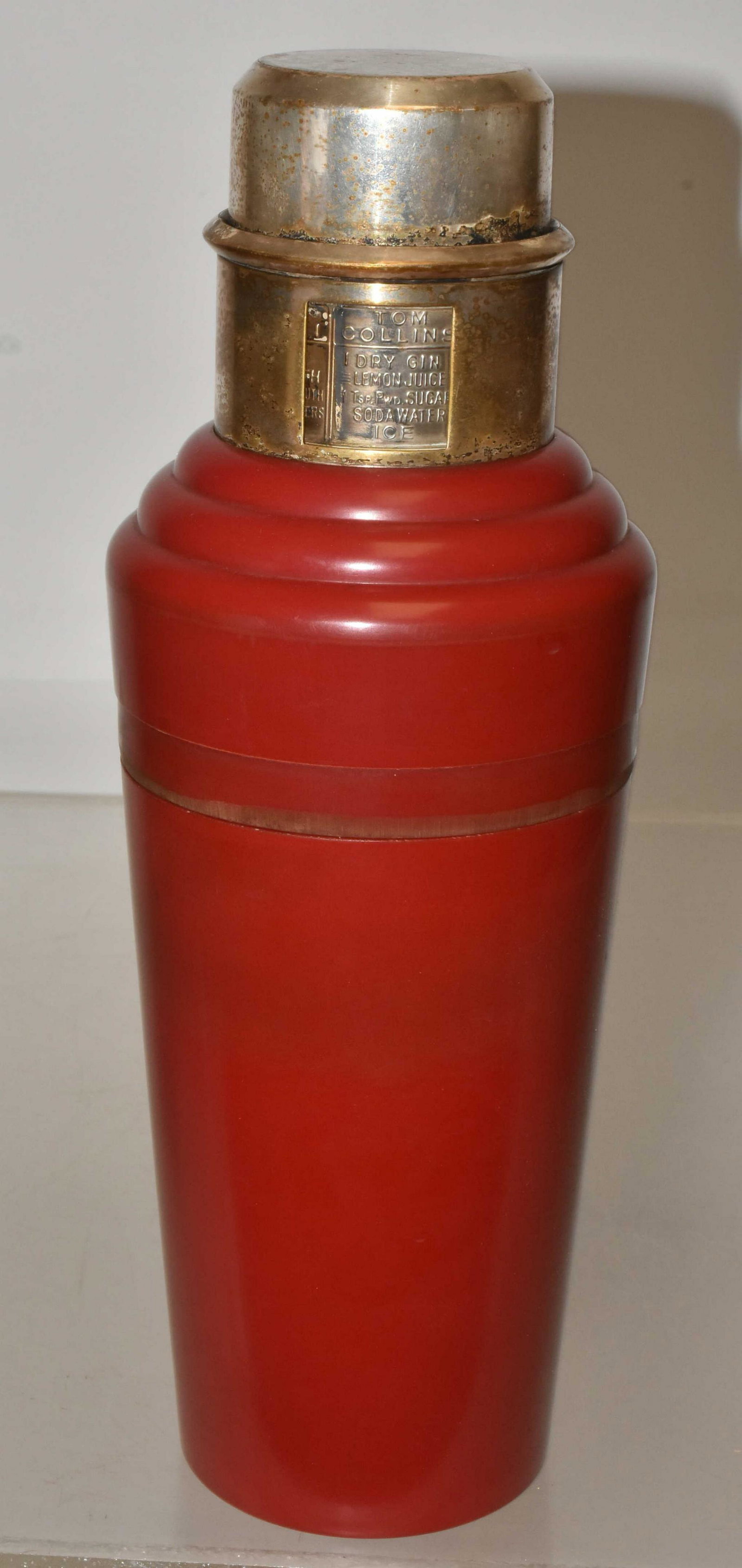Urea Formaldehyde Raphael & Clark Cocktail Shaker: Approximately 11"H. Designed by Raphael & Lawson Clark. Red master color. Chromium top with turning ring recipe collar. 2 piece body with internal colander. Missing silver plated band at closure. Manu