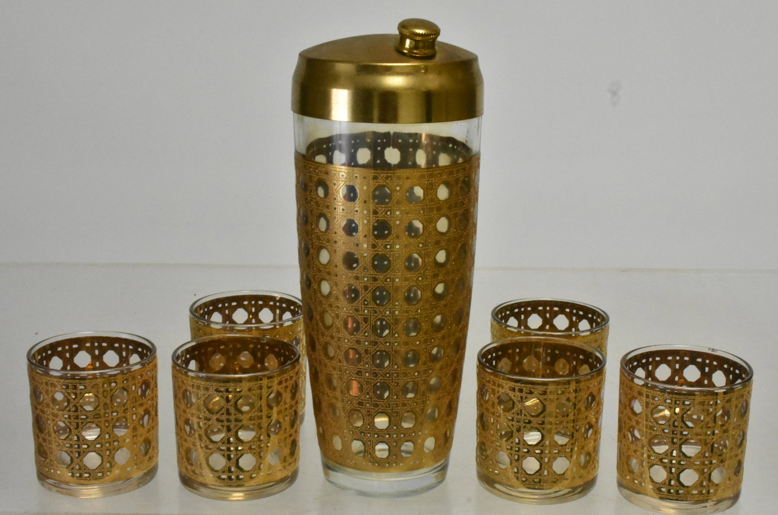 Culver Cannella 22k Gold Cocktail Set: Cocktail shaker measures 9.5"H. 22K gold rattan basket weave pattern over glass bodies. Gold is in good condition. Set has no visible flaws.