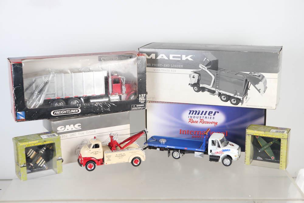 Die Cast Vehicles with Boxes (6): Lot includes a Miller International Rollback, a First Gear GMC tow truck, a Freightliner garbage truck, a Mack garbage truck with trash bin, and (2) small military airplanes. All items are in box.