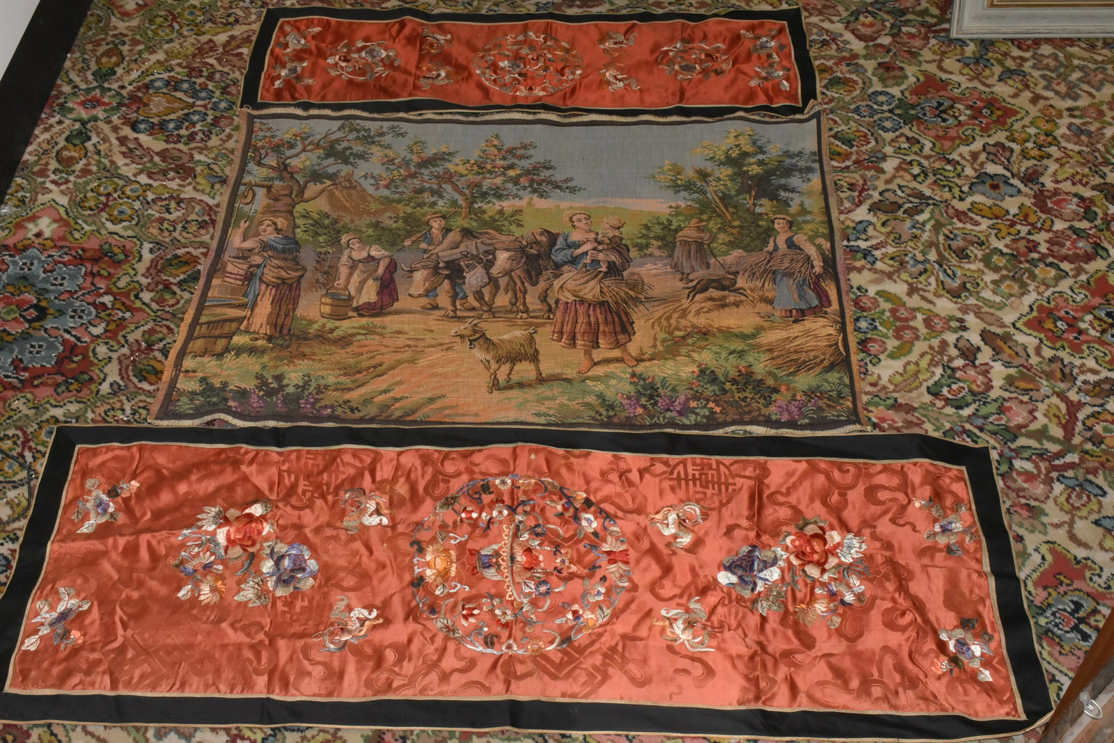 Asian Table Silk and European Tapestry: Lot includes (2) Asian table silks with cotton backing (largest measures 45"L). Floral motif on both. Matched pair. Lot also includes a Belgium tapestry with a farm scene.