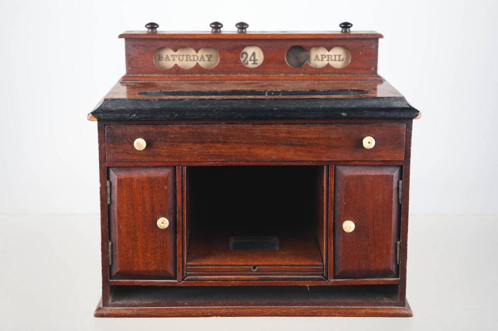 Pen & Ink Stand in Form of Desk, 19th C: Approximately 9.5"H x 11"W x 6.5"D. Pen stand dish in the form of a desk. Old tack nail drawers, bone knobs, calendar paper day and date adjustment, two cabinet drawers, and central pullout. Bottom Sl