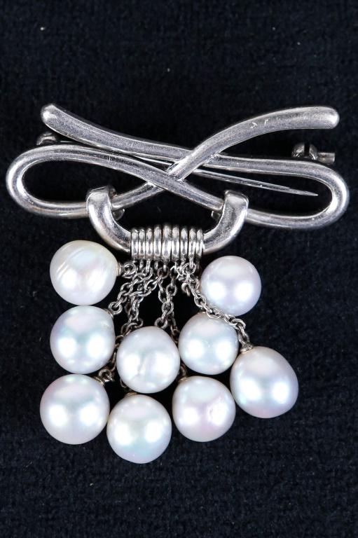 Vintage Signed "Mikimoto" Sterling Brooch: Signed "Mikimoto Sterling". Bow tie design with nine large gray pearls suspended from a sterling chain in a signature cluster design. Signed "K. Mikimoto Tokyo NS".