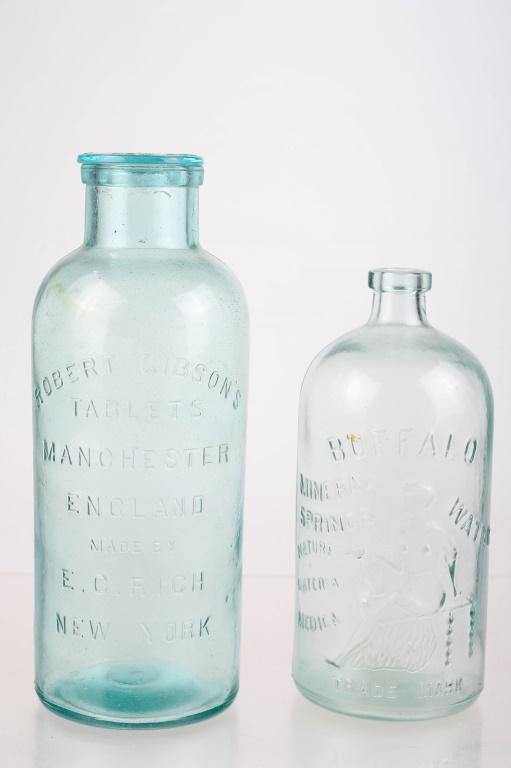 19th C. Graphic Advertising Bottles: includes a Robert Gibson's Tablets bottle measuring approximately 13"H, with glass cap; and a Buffalo Mineral Spring water bottle with a figure of a woman. Bottles have no visible flaws.