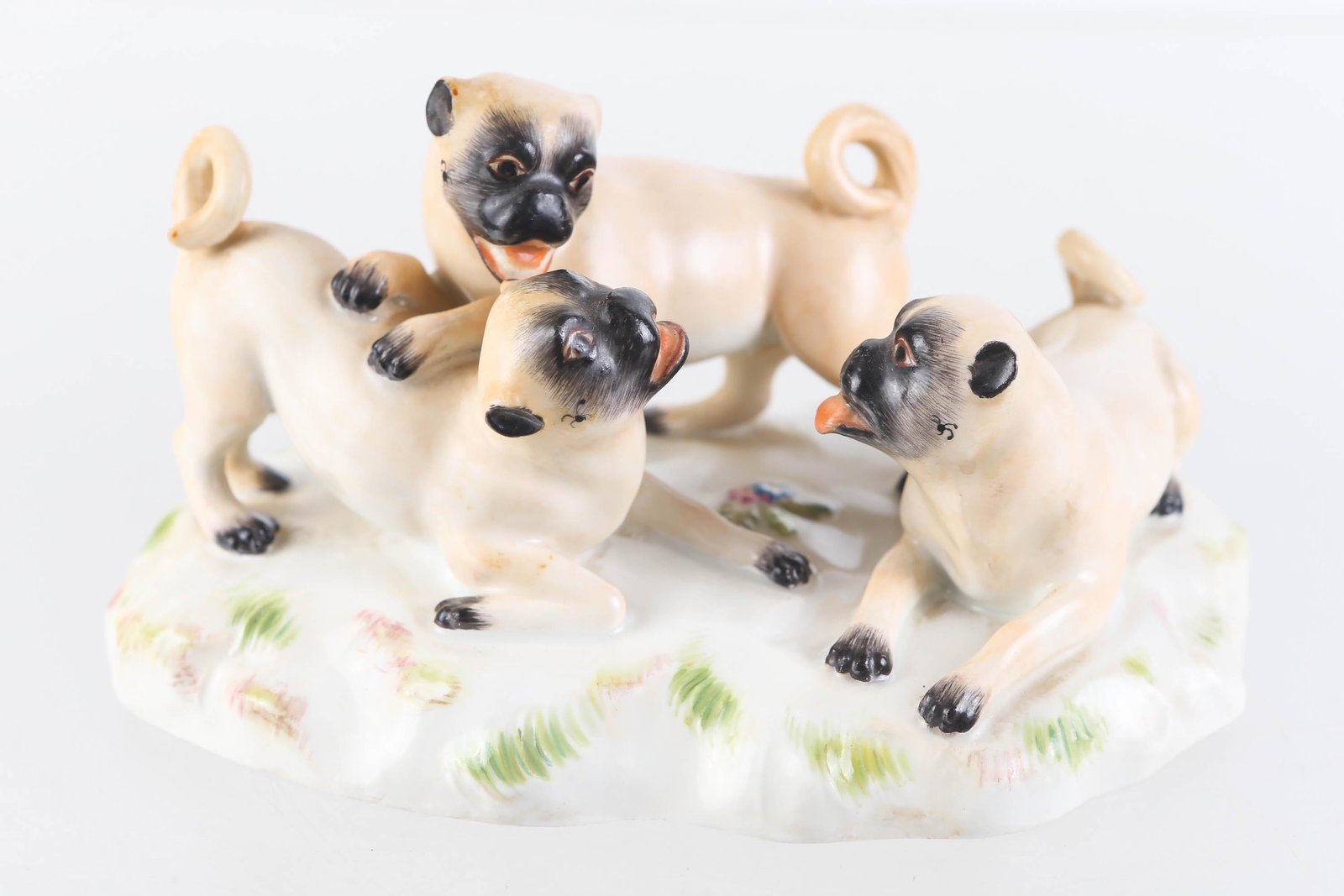 Meissen Figure of Three Pug Dogs: Figure measures approximately 3.5"H and 6" across. It depicts three pug dogs at play. Meissen mark on bottom. No visible flaws.