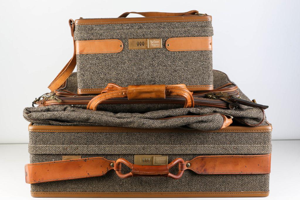 Hartmann Tweed Luggage: includes tweed suitcase with leather handle (8"H x 26"W x 19"D), a suit bag, a soft carry bag, and a small vanity box with mirror. All are marked Hartmann luggage and are in moderately used condition.
