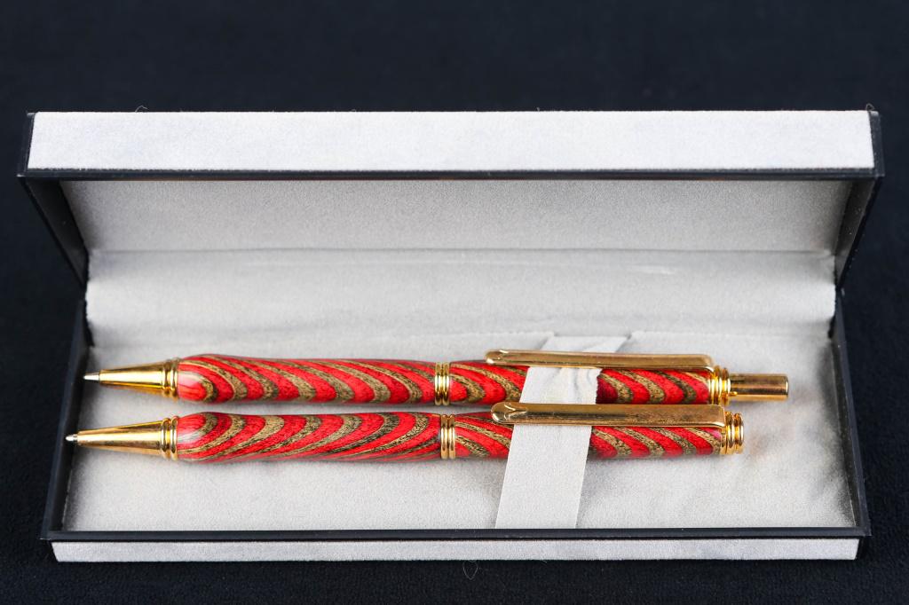 Hand Turned Red Pen Set: Item has red and natural hand turned wooden body with gold tone mounts. Clips are marked with a V. Item comes in original case.