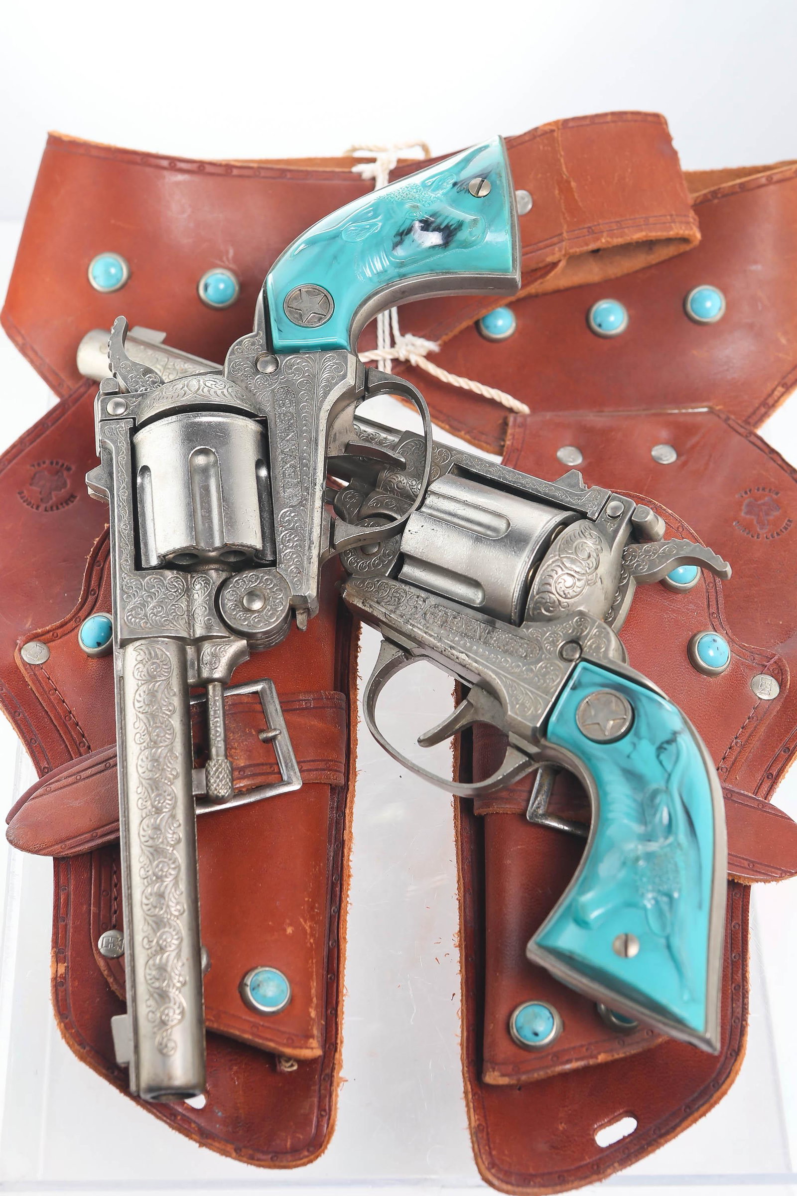 Texan 38 Revolver Cap Guns, Pair in Double Holster: Leather holster is decorated in faux turquoise throughout. Marked "Top Grain Saddle Leather" and has bullet storage on belt with some bullets inserted. Cap guns both function great. Both handles are f