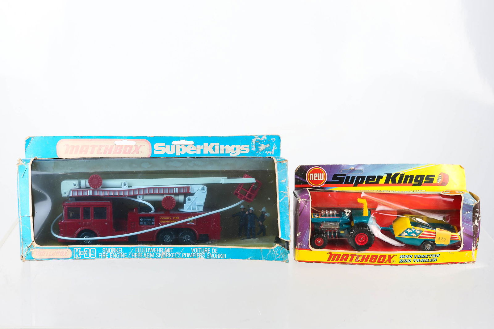 Two Matchbox Super Kings in Original Boxes: First is a Snorkel fire engine K-39 never removed from packaging with 3 figures of firemen, measures 10" long, and made in 1981. Second car is K-3 Mod Tractor and trailer. Toy looks new in packaging w
