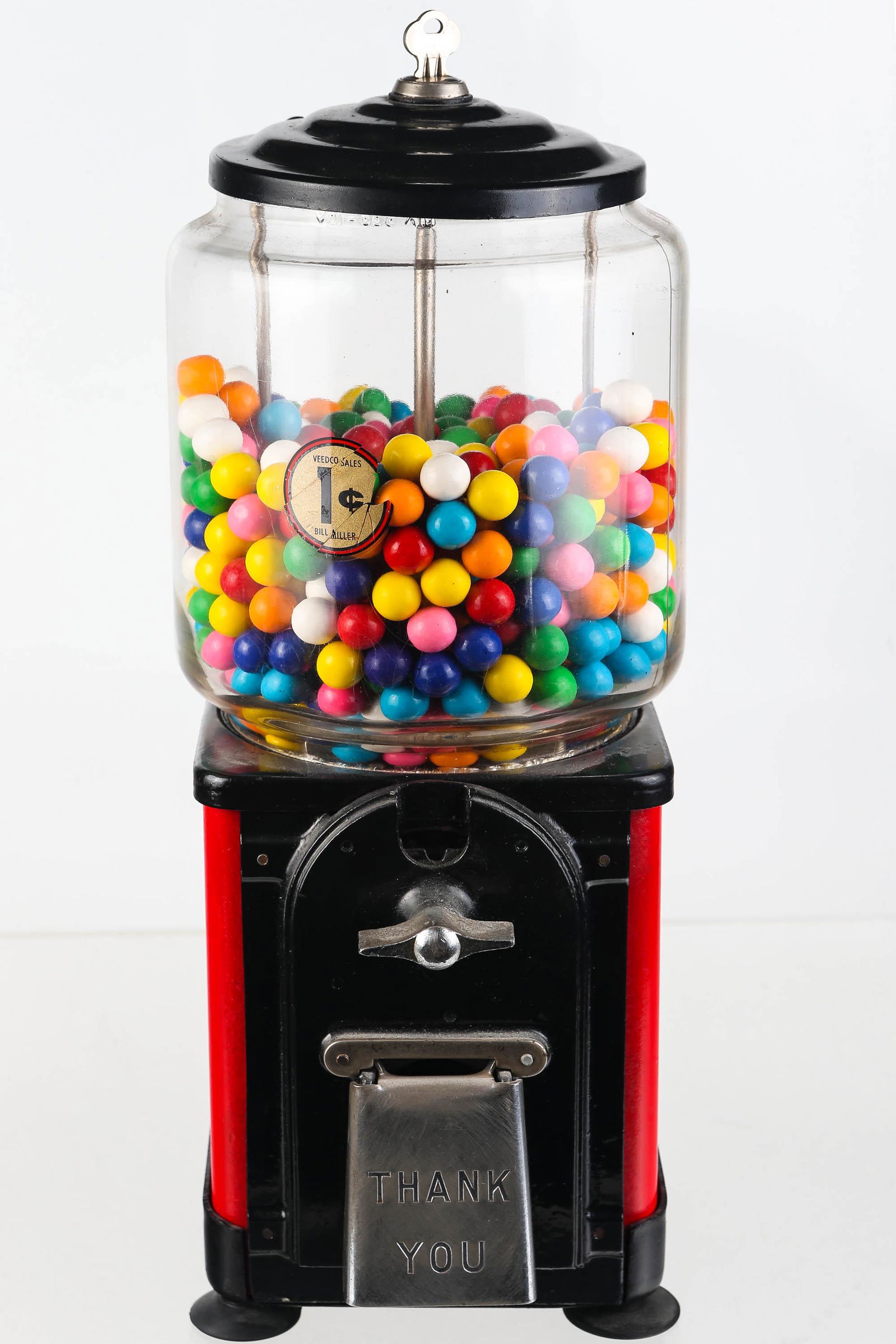 Vintage 1 Cent Gumball Machine: Metal body is painted black and red with glass globe on top. Decal on top reads Veedco Sales 1 cent Bill Miller (decal on inside). Machine comes with a key but locking mechanism is stripped when attem