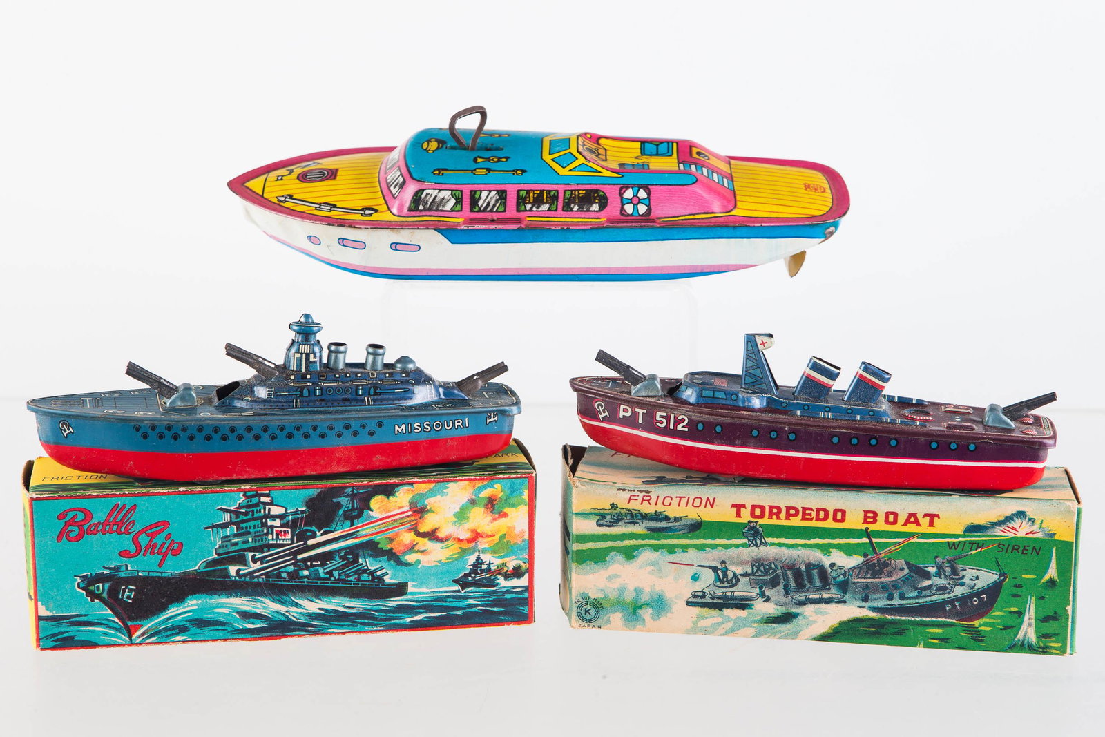 Tin Litho Friction and Wind Up Boats: Two Japanese battleships with boxes. Each ship approximately 6.25"L. Both have good lithography. One item is PT512, the other is the Missouri. In original boxes. Lot also includes a J. Chein wind up b