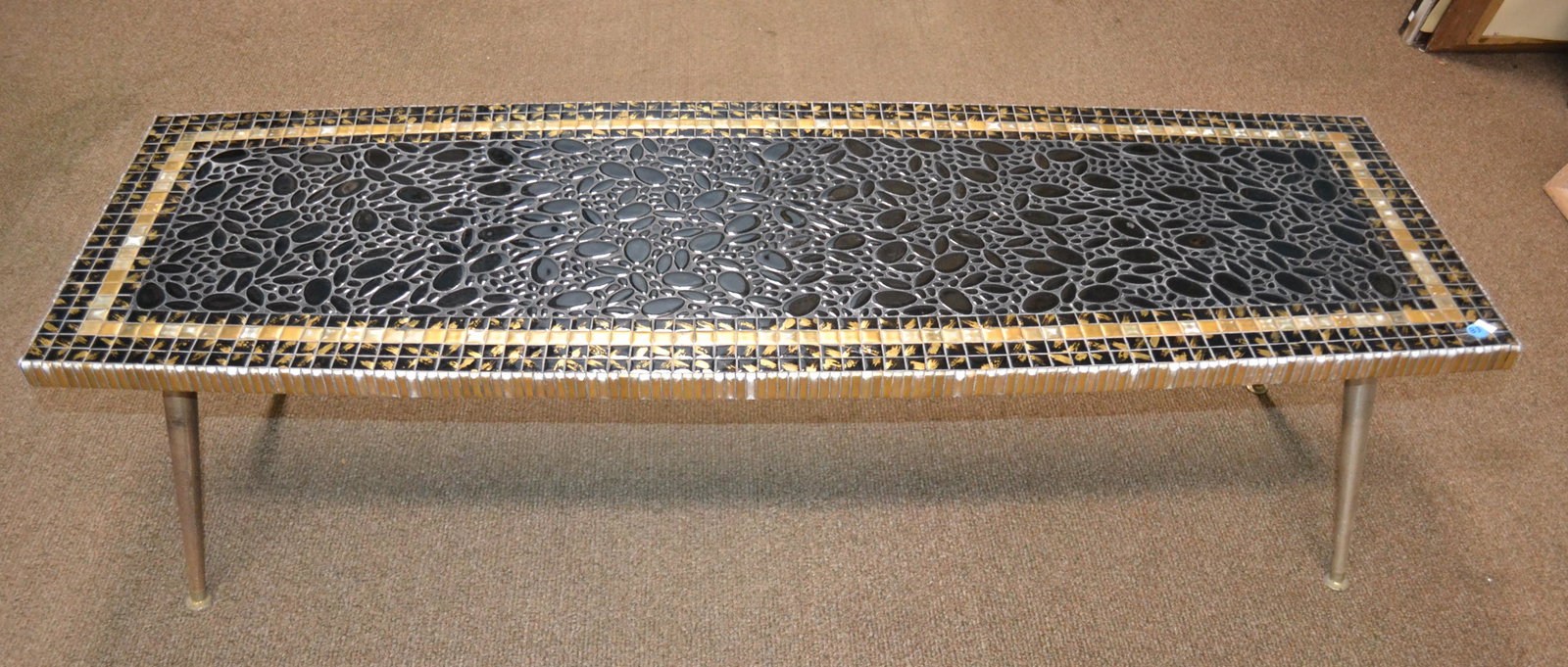 Mid Century Modern Mosaic Tile Coffee Table: Approximately 15.5"H x 54"W x 18.5"D. Table has mosaic tile table top with gold splashing detail on wood frame with metal legs. Slender shape. Tile on the edging too.