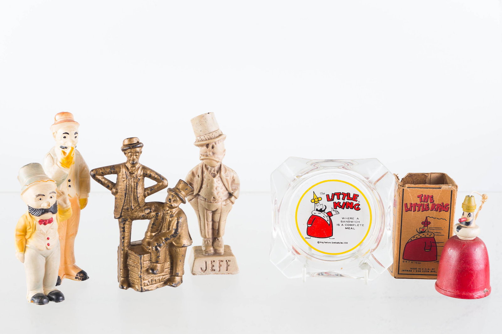 Mutt and Jeff, and Little King Grouping: Lot includes two piece cast Mutt and Jeff figure, Mutt and Jeff celluloid figures (Jeff damaged at head), ceramic Jeff figure, Little King wooden string toy (box dated 1939), and Little King ashtray r