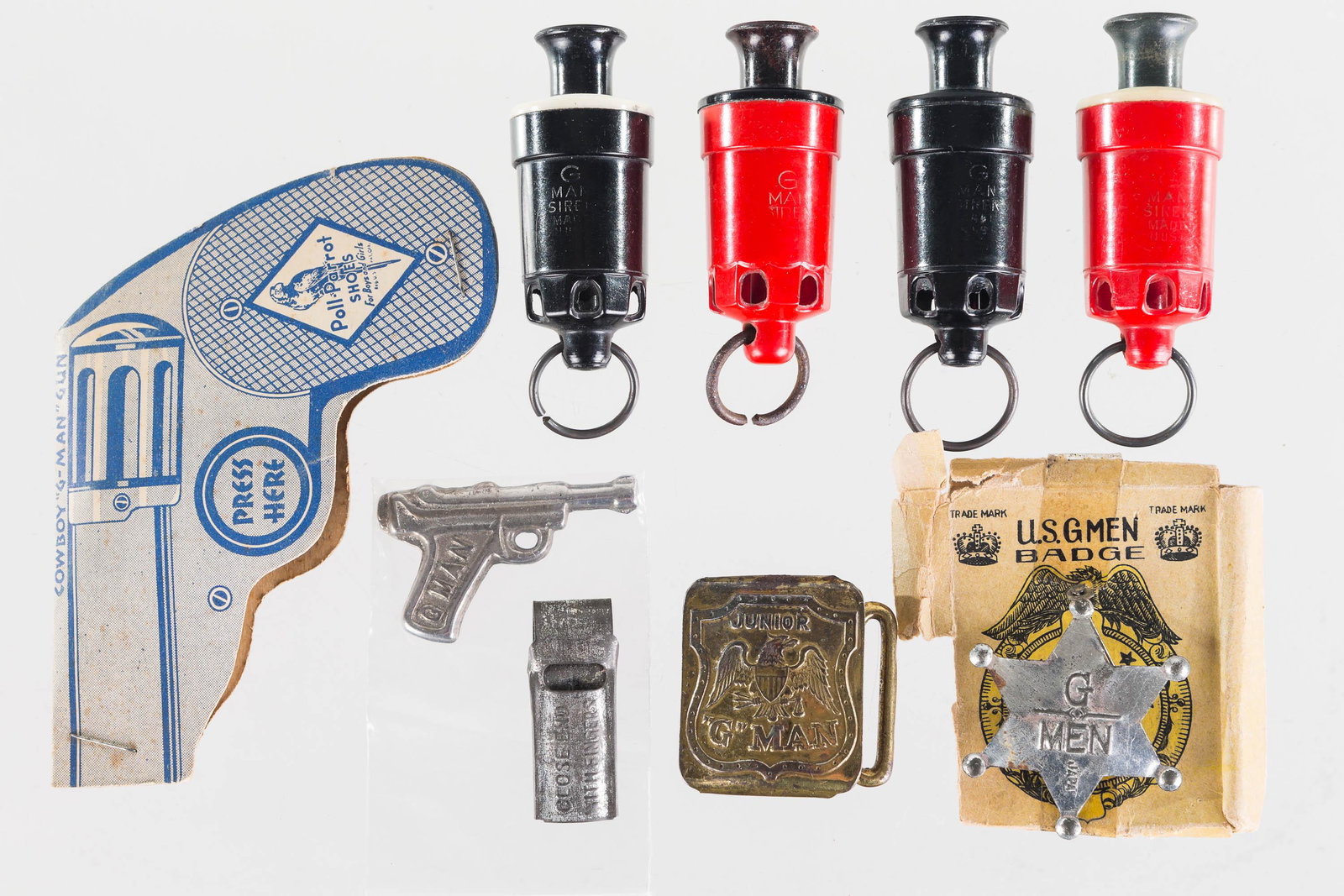 G-Man and Related Toy Grouping: Lot includes Junior G-Man belt buckle, G-Men badge with box top, four air sirens (one marked John Lauterbach Company, Phila, PA), miniature G-Man pistol, and a paper G-Man click gun from Poll Parrot S