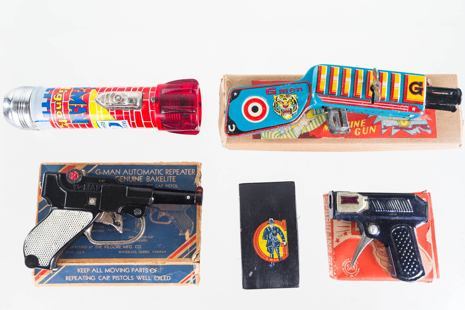 G-Man Guns and Accessories: Lot includes K Brand Kilgore functional luger cap gun with clip (with original box, missing flaps), tin litho G-Men functional cap gun by TN Toy Japan (with box), a SAND Japanese G-Man sparkling gun i