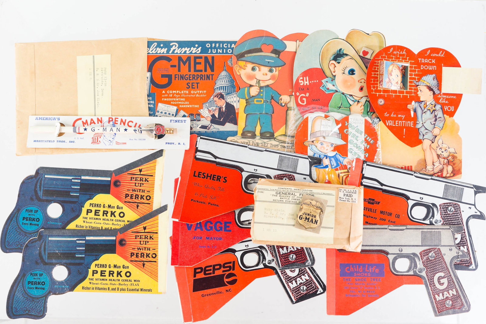 G-Man Advertising and Toys: Lot includes 7 cardboard advertising guns, 4 G-Man and police oriented Valentine cards, G-Man pencil on hang card, metal Junior G-Man badge in original shipping envelope, and a G-Man fingerprint set f