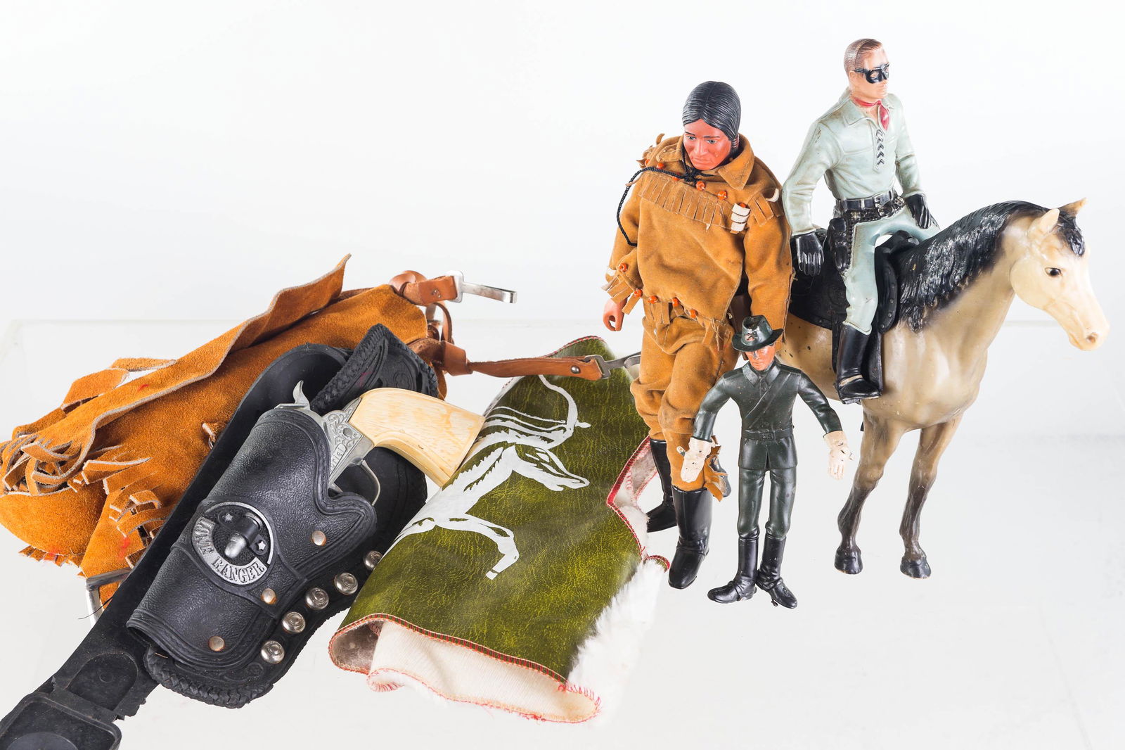 Western Toys and Costume: Lot includes Lone Ranger Gabriel Cap Gun in holster, Tonto figure with horse, Lone Ranger solid figure, a flexible cowboy figure, children's suede chaps, and children's Western vest
