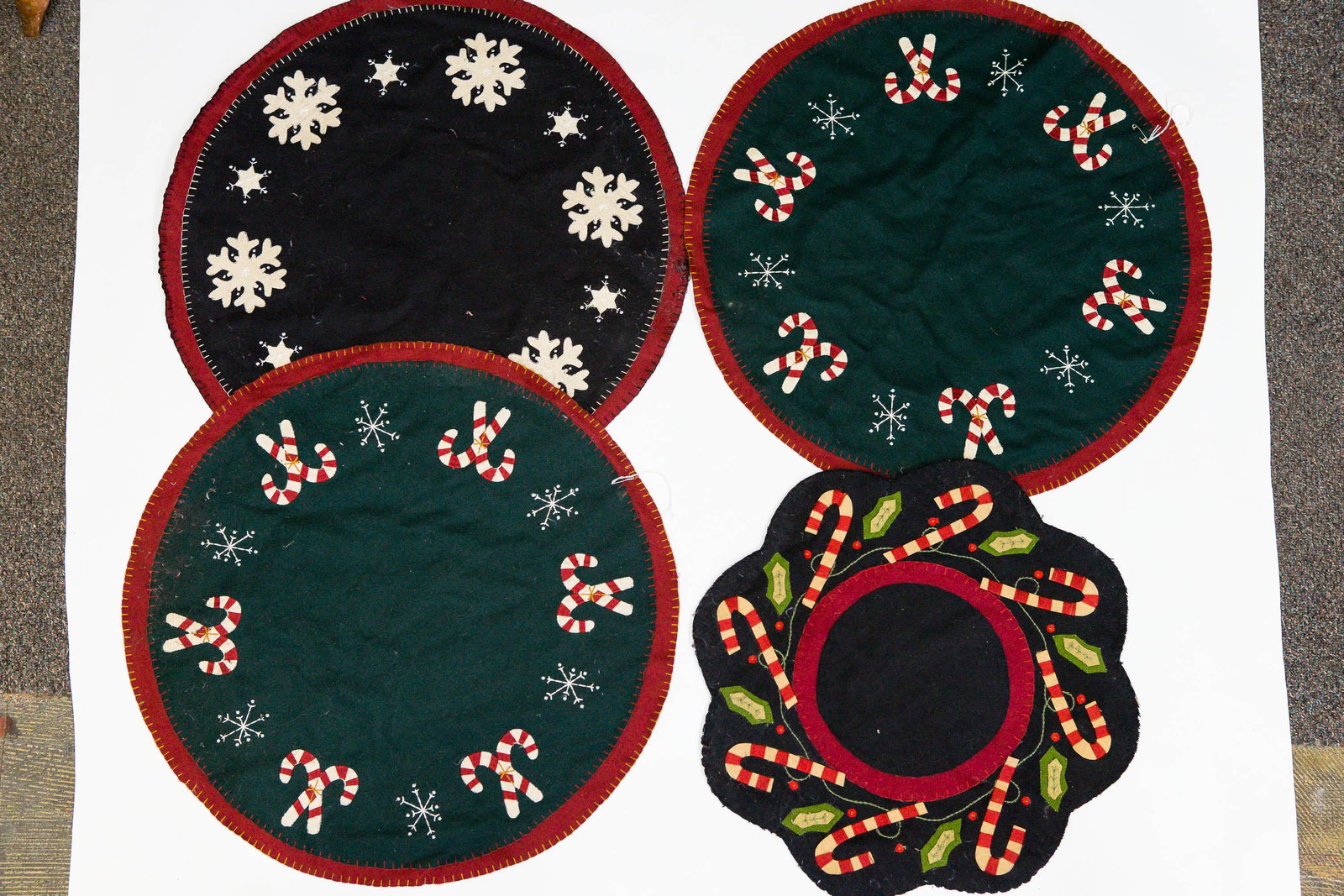Hand Stitched Applique Christmas Table Mats: Lot includes 4 mats (3 largest 23" diameter). All have Christmas motifs. Lot also includes one mat (20" diameter) with candy cane motif. Some show common wear